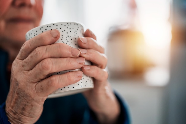 View of hands of a senior woman hold a cup close up