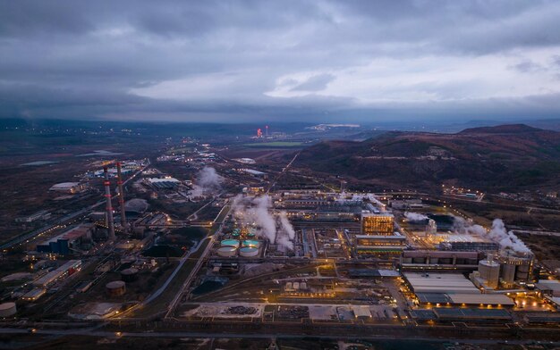 View of a heavily smoking factory at night industrial area aerial view