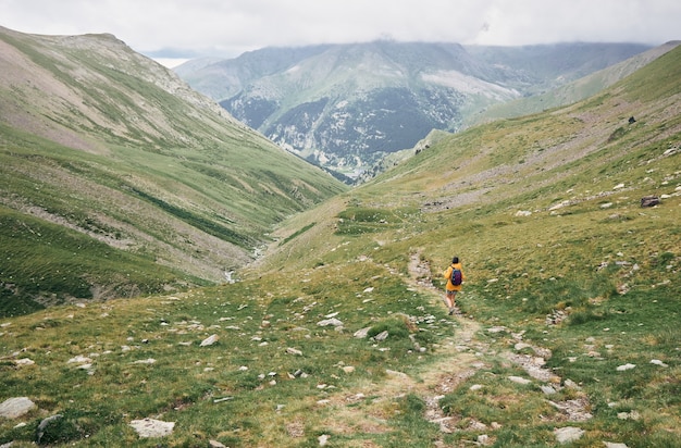 View of a hiker walking on a path between the mountains