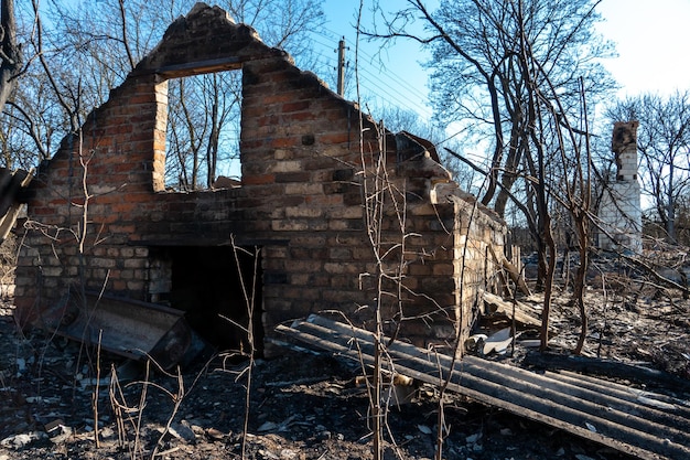 Вид на разрушенный после пожара дом Последствия лесного пожара в деревне Обугленные стены кирпичного дома крупным планом