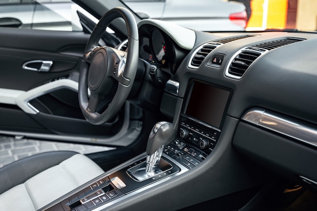 Foto vista dell'interno di un'auto decappottabile di lusso, cruscotto moderno con touch screen, sedili in pelle bianca ideali per il conducente. messa a fuoco selettiva.
