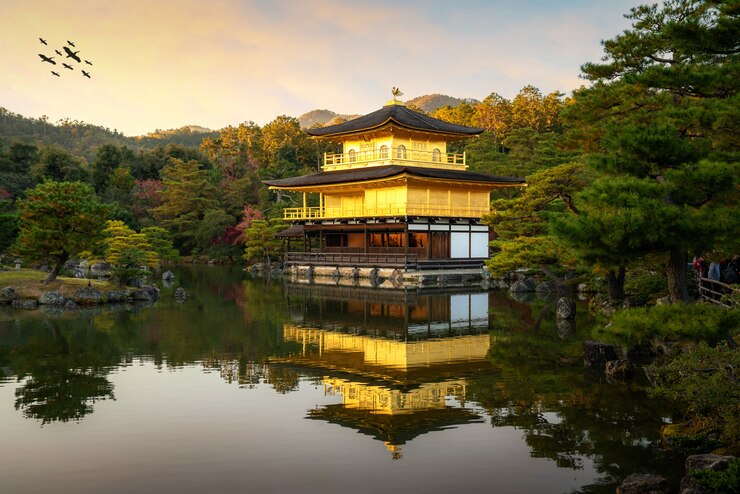京都の秋のシーズンに日本庭園と劇的な夕方の空と池がある有名な金閣の金閣寺の景色。