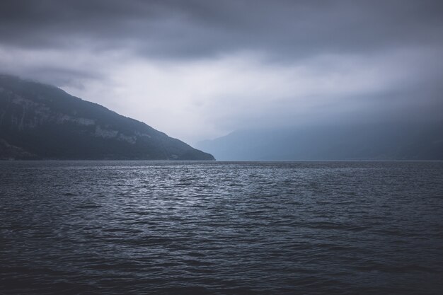 View on lake Thun and mountains from ship in city Spiez, Switzerland, Europe. Dramatic moody blue clouds scene