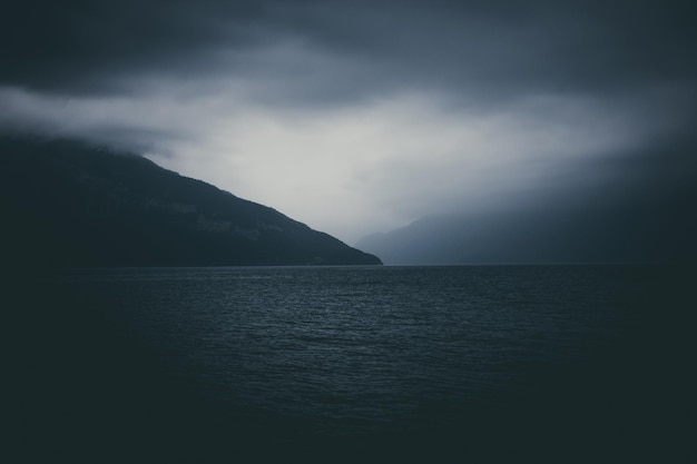 Photo view on lake thun and mountains from ship in city spiez, switzerland, europe. summer landscape. dramatic moody blue clouds scene