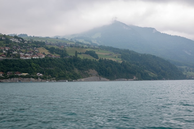 Vista sul lago di thun e sulle montagne dalla nave in città spiez, svizzera, europa. paesaggio estivo. scena drammatica lunatica nuvole blu