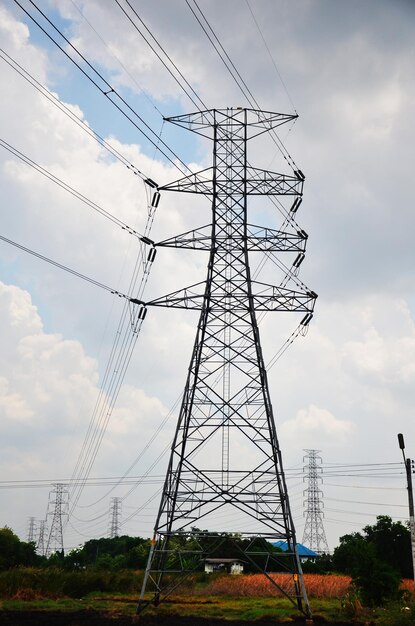 View landscape countryside with high voltage utility pole column for local electric supply steel post support overhead power lines on pathway of rural country village valley at Bangkok Thailand