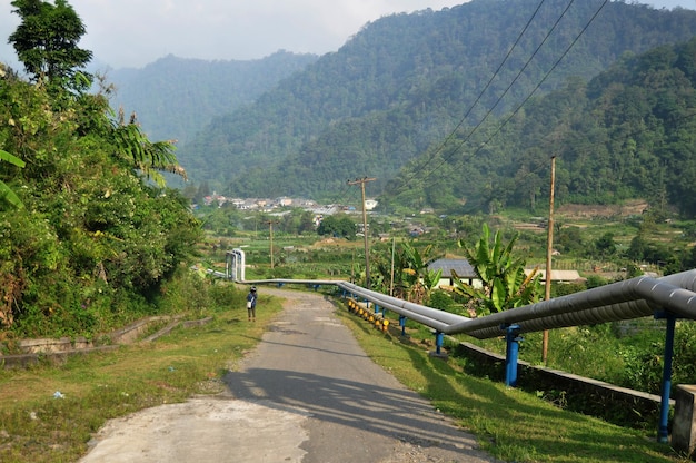 Photo view landscape mountain and water and gas pipe line transfer to raja berneh city valley village hill for indonesian use in sibayak mount of karo at sumatera utara or north sumatra indonesia