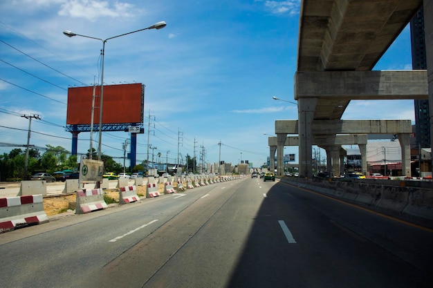 Вид на ландшафтную дорогу и строительную площадку со строителем тяжелой техники, строящим новый бетонный автомобильный мост на городском пейзаже города Банг Яй 18 июня 2022 года в Нонтхабури, Таиланд