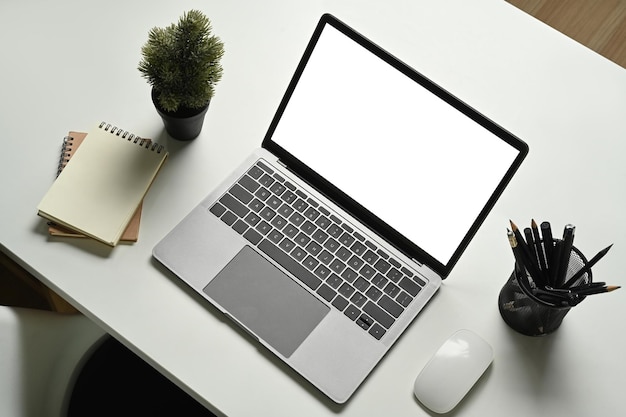 Above view of laptop computer potted plant and stationery on white office desk Home office modern workplace