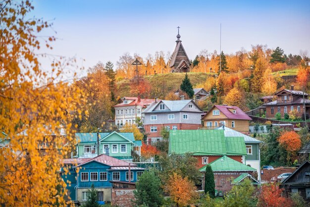 Photo view of levitan mountain with a church and houses among red autumn trees on a cloudy afternoon