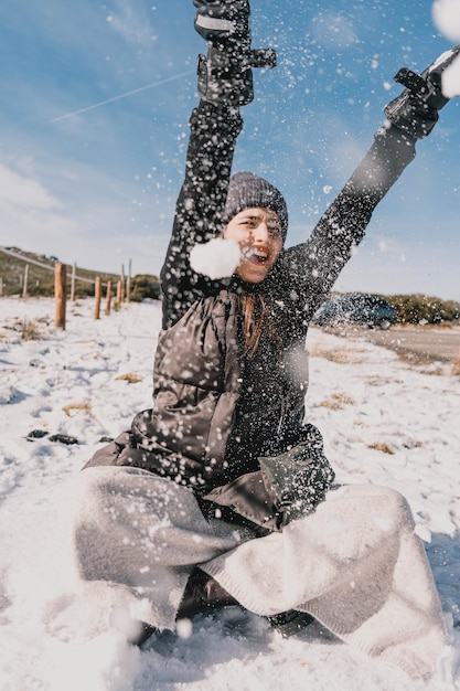 Foto vista di una bella donna caucasica che si diverte nella neve in una giornata di sole