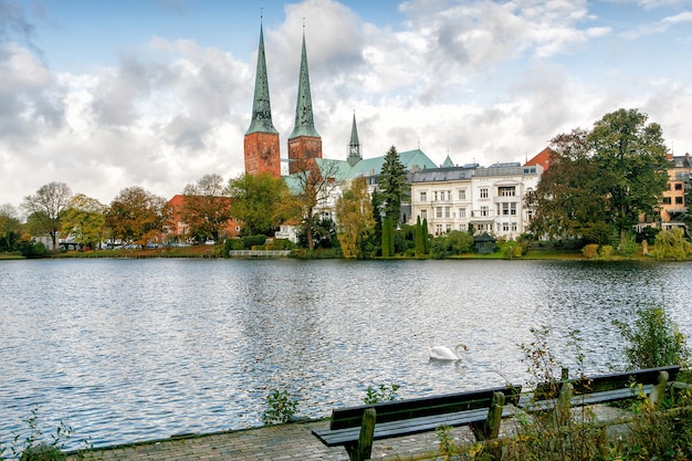 Photo view of lubeck the white swan is swimming in the lake. cathedral from muhlenteich (mill pond) in autumn, germany.