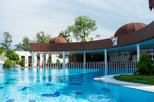 View of the luxurious outdoor pool with clear blue water and a white rotunda with bridges