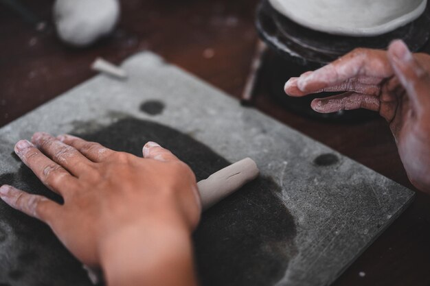 View of male hands works with clay makes future ceramic plate\
ceramic artist makes classes of hand building in modern pottery\
workshop creative people handcrafted design