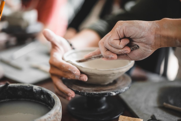 View of male hands works with clay makes future ceramic plate
ceramic artist makes classes of hand building in modern pottery
workshop creative people handcrafted design