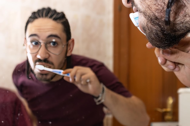 Foto vista dell'uomo lavarsi i denti nello specchio del bagno riflessione dell'uomo lavarsi i denti nel bagno