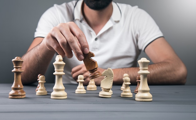 View of a man holding a chess piece in his hand on a gray wall