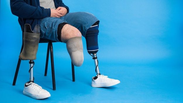 View of a man with prosthetic legs and white sneakers sitting\
on a chair with removed prosthesis