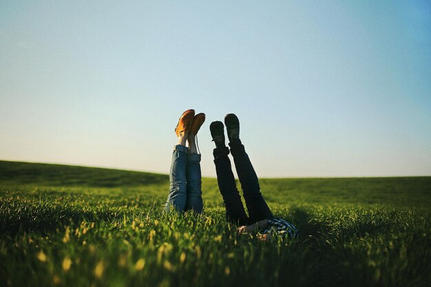 View of a mans and womans legs sticking up out of tall green grass on summer dayselective focus nois