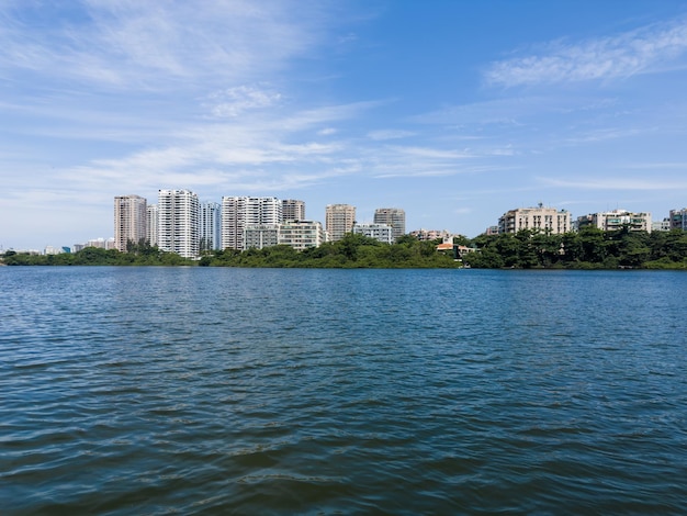 배경에 건물이 있고 주변 식물과 나무가 있는 마라펜디 석호의 전망 리우데자네이루의 Praia da Reserva 근처에 위치 배경에 있는 언덕