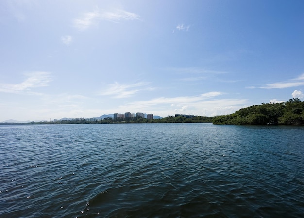 View of the Marapendi lagoon with buildings in the background and surrounding vegetation and trees Hills in the background Located near Praia da Reserva in Rio de Janeiro