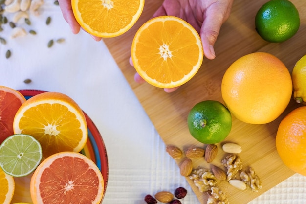 Above view of mature woman's hands holding an orange cut in half to make healthy juice. Healthy and dietary lifestyle