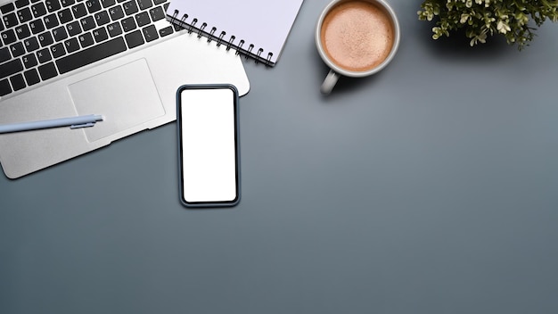 Above view mock up smart phone, computer laptop, notebook and coffee cup on gray background.