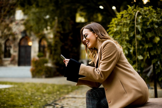 View at modern woman using mobile phone at autumn outdoor