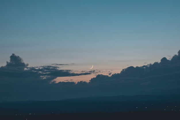 Photo view of the moon through the clouds at sunset