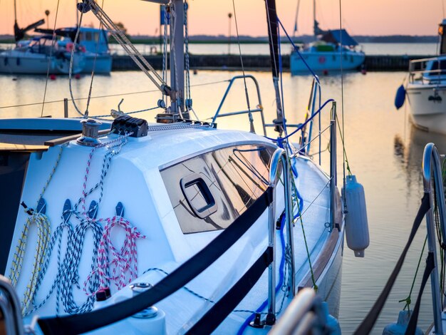 Foto vista su scafo di yacht a vela ormeggiato e attrezzature su un molo vista del paesaggio acquatico all'alba