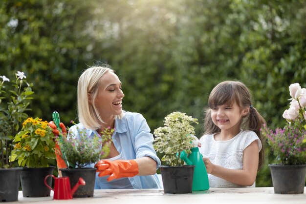 Photo view of mother and daughter watering plants outdoors