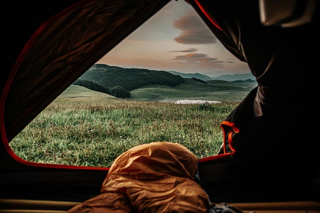 View of mountains covered in greenery from a tent in the evening