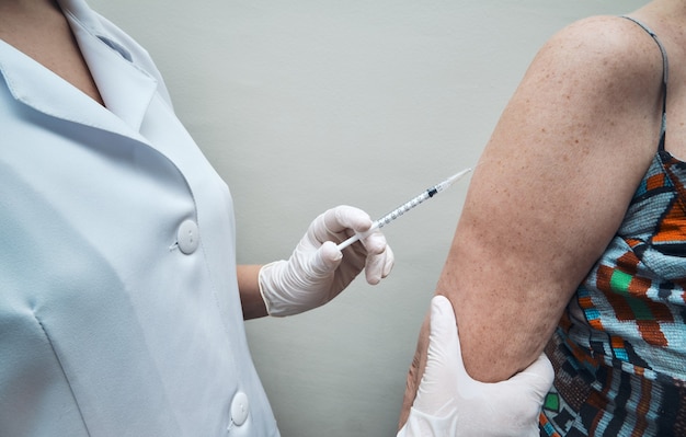 View of nurse vaccinating elderly womans arm.