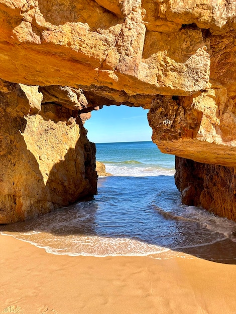 A view of the ocean through the natural limestone arch on the sandy beach of Algarve Portugal