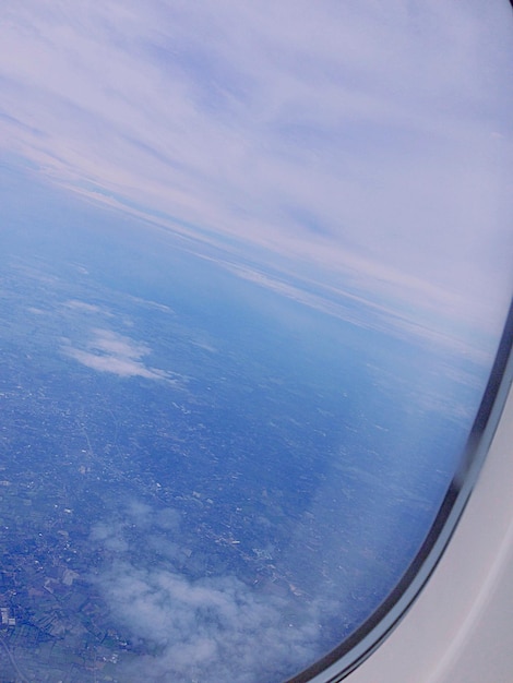 写真 飛行機の窓から見える雲の空の背景にある風景