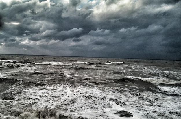 写真 雲の空に照らされた嵐の海の景色