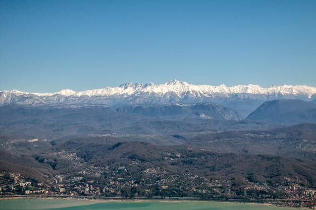 写真 海辺の街と雪で覆われた高い山の景色