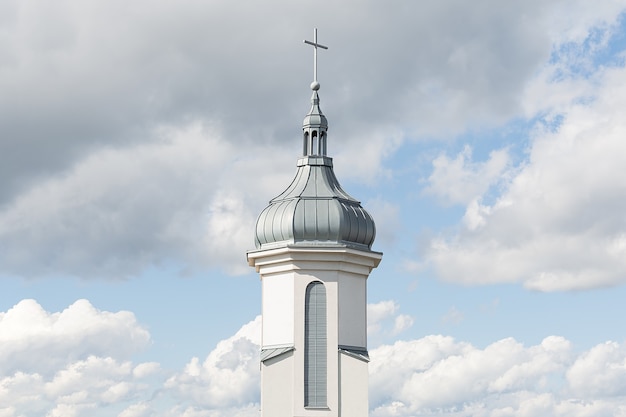 Фото Вид на купол и колокольню современной католической церкви на фоне голубого неба с облаками. концепция архитектуры, пасхи, религии.