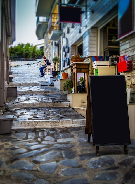 사진 선술집 메뉴와 광고가 있는 스코펠로스 섬 그리스의 좁은 거리 전망