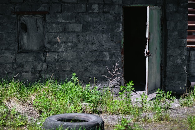 Photo view of an old abandoned building, which boarded up the window and open the door in the summer.