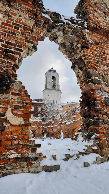 View of old Clock Tower through ruined brick wall Belfry of Vyborg Cathedral