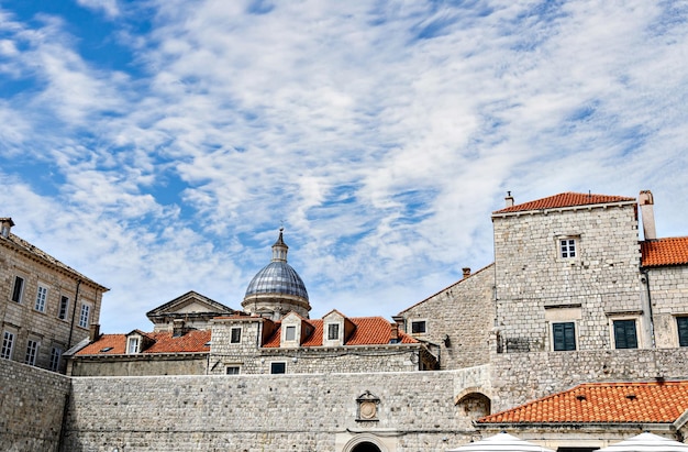 크로아티아의 흰 구름이 있는 푸른 하늘 아래 벽 뒤에 있는 두브로브니크 구시가의 전망을 감상하실 수 있습니다.