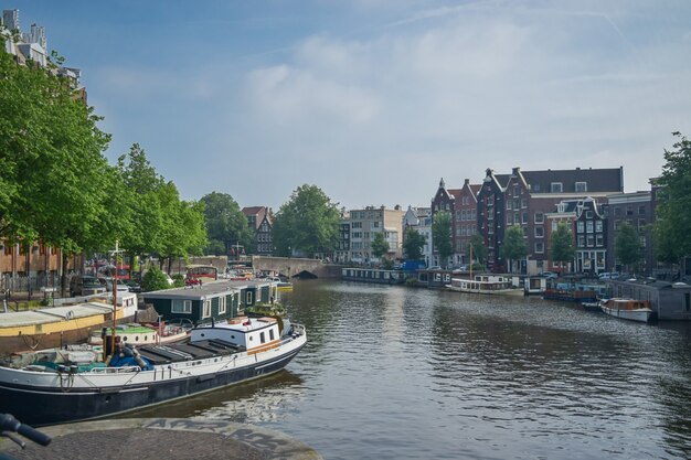 View of one of the canal and boats with an old building in the background in Amsterdam, Netherlands