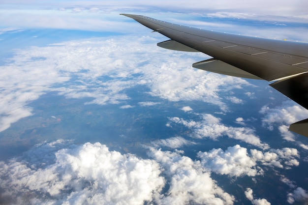 航空機の翼の窓と雲の切れ間からブラジルの風景を眺める