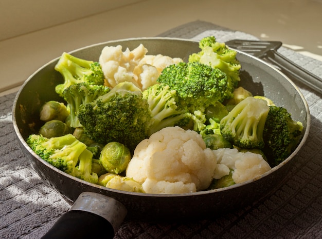 Photo view of the pan with fresh defrosted vegetables and kitchen spatula