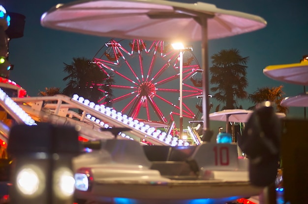 Vista di una ruota panoramica con il tramonto alle spalle, scattata in un luna park in una località balneare.