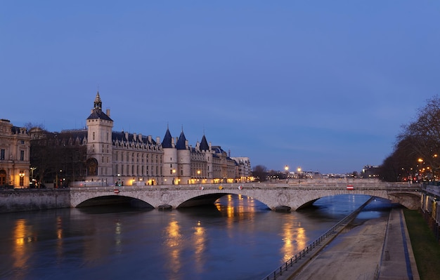 View of Paris by night with a bridge over the Seine river and the Conciergerie building