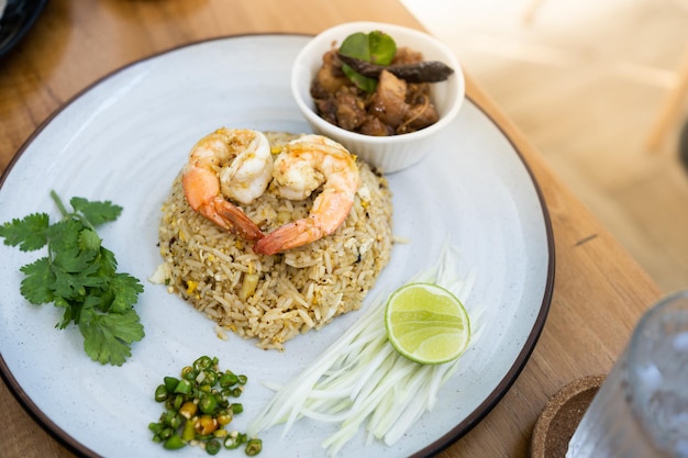 A view of a plate of shrimp fried rice in wood table on a restaurant