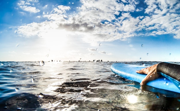 Punto di vista del surfista che si rilassa sulla tavola da surf al tramonto in attesa della prossima onda