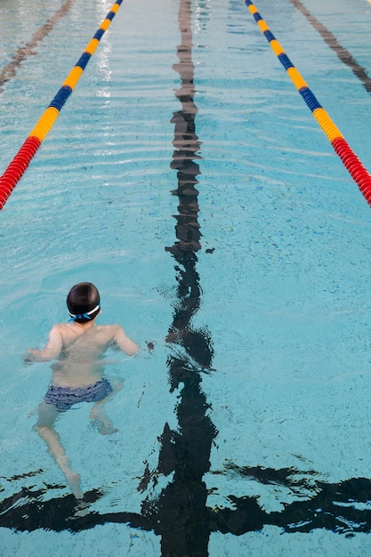 La vista di una piscina pubblica al chiuso corsie di un concorso ragazzo che si allena in una piscina